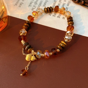 Détails des pierres œil de tigre, perles en bois et breloque gourde dorée du bracelet