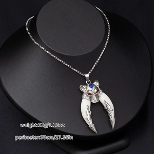 Detail of silver wolf head necklace with red eyes, blue gem, and white tusks on black stand