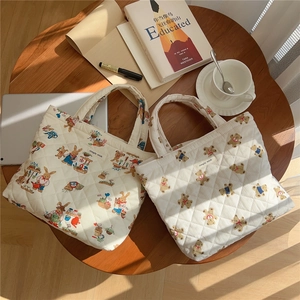 Close-up of quilted tote bags featuring cute bear and rabbit prints on a wooden table