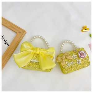 Detail of yellow tweed kids bags with pearl handles and decorative bows for girls