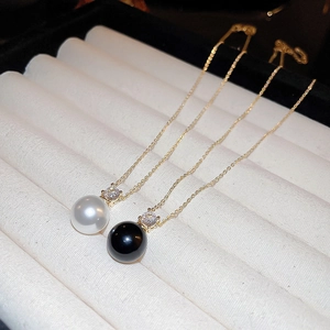 Elegant gold pendant necklaces featuring white and black pearls with sparkling zircon accents