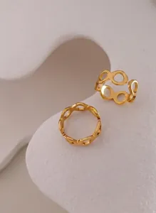 Detail of 18K gold-plated titanium figure-8 hollow open ring on a textured stone