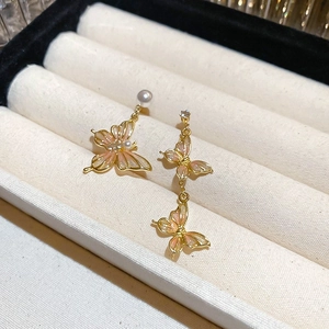 Détail macro de boucles d'oreilles papillon roses asymétriques avec perles et écrin