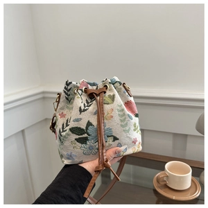 Detail of ethnic floral tapestry bucket bag with brown faux leather drawstrings and strap