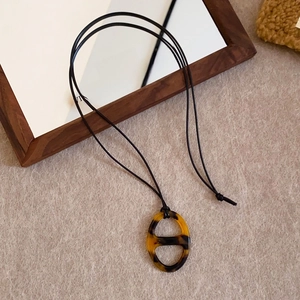 Detailed shot of amber resin pig nose pendant on minimalist black cord necklace
