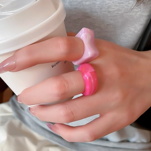 Close-up of pink marbled acrylic resin rings worn while holding a white coffee cup