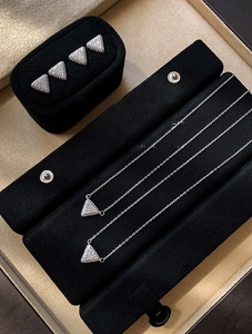 Detailed view of silver zircon triangle stud earrings and necklace set on velvet tray