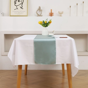 Detail of light blue satin table runner with a smooth texture on a white tablecloth
