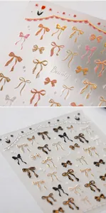 3D textured gold bow nail stickers with floral accents and beauty lettering detail