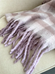 Close-up of soft pink and purple plaid scarf showing textured fabric and tassel fringe