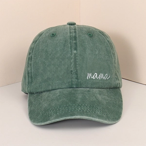 Detailed close-up of white mama embroidery on washed green cotton baseball cap fabric