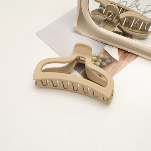 Detail of a large matte cream hair claw clip with minimalist interior design decor