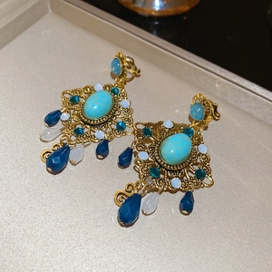 Close-up of vintage gold hollow woven earrings with turquoise stones and blue resin drops