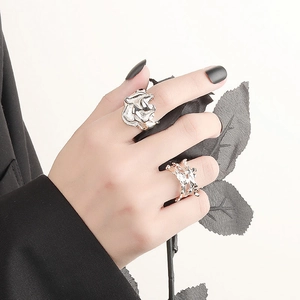 Irregular textured silver floral and rose gold coral rings on hand with black rose