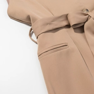 Detail of khaki vest with flap pocket, waist tie, and amber button texture