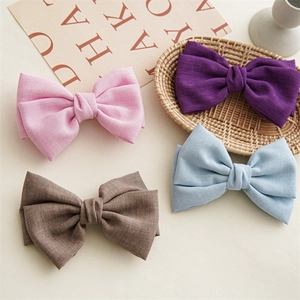 Detailed macro view of four pastel linen fabric bow clips on a bamboo tray