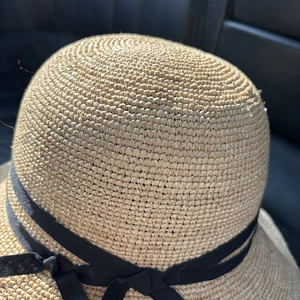 Nahaufnahme der handgewebten Raffia-Struktur und schwarzen Schleife am Sonnenhut