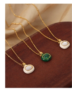 Detail of vintage gold plated necklaces with malachite and white shell pendants on wood