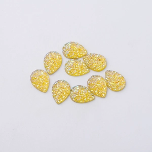 Macro shot of yellow teardrop resin charms with glitter texture for DIY jewelry making