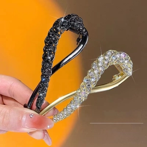Close-up of elegant twisted hair clips with black and gold rhinestones held by hand