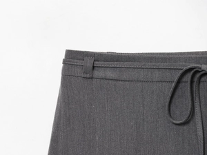 Dettaglio della vita alta con coulisse e passanti per cintura su gonna in twill grigio