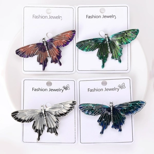 Flat lay of four colorful butterfly brooches in gradient enamel on a white plate