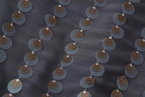 Detail of dark grey chiffon fabric with layered brown sequins and metallic rivet accents