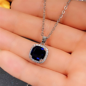 Detailed close-up of a silver necklace featuring a square navy blue gemstone pendant