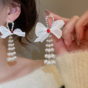 Detail of bowknot pearl tassel earrings with red gemstone and silver needle stud