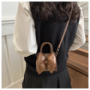 Brown mini crossbody bag featuring a large decorative bow and elegant leather texture