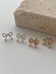 Detailed macro shot of luxury rhinestone bow earrings in silver and gold finishes
