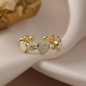 Exquisite gold-plated shell heart ring with zircon accents on a beige fabric background