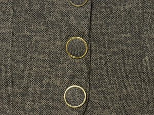 Close-up of olive green knit fabric texture with decorative gold round buttons