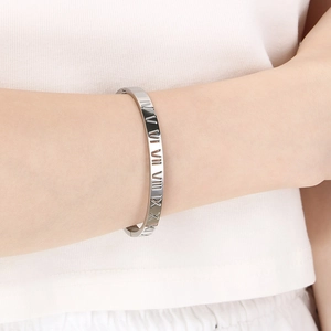 Détail du bracelet argenté avec chiffres romains ajourés porté au poignet, fini poli