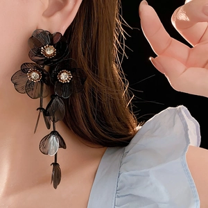 Détail de longues boucles d'oreilles fleurs en maille noire avec strass blancs