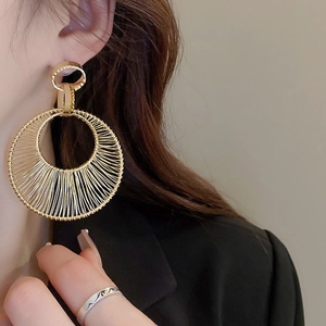 Close-up of golden hollow metal hoop earrings with textured wire-wrapped detailing