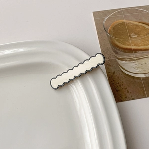 Close-up of minimalist cream and black checkered hairpin on elegant ceramic plate