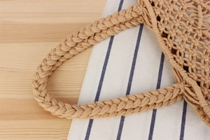 Close-up of beige woven cotton rope handles on a minimalist summer beach tote bag
