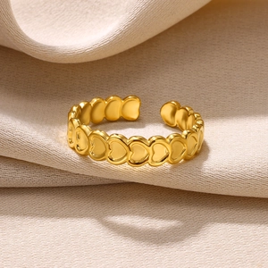 Detail of matte gold heart-shaped ring with a textured finish on a beige fabric background