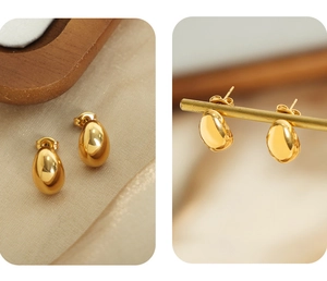 Detailed close-up of polished gold oval stud earrings on silk and brass display stand