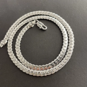Coiled 5mm silver cuban link chain necklace with lobster clasp on dark grey background