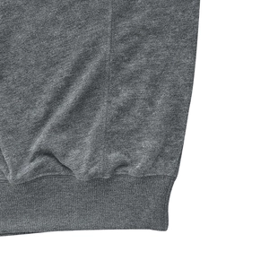 Macro detail of men's distressed grey knit hoodie showing ribbed hem and texture