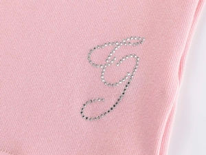 Close-up of pink ribbed fabric with silver rhinestone letter J detail and knit texture