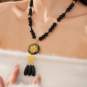 Detail of vintage beaded necklace with gold flower pendant, bow and black teardrop tassels