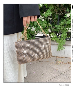 Detailed view of elegant gold rhinestone clutch bag with interwoven metal chain handles