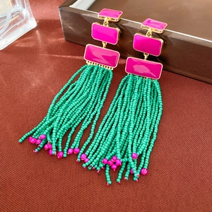 Detail of bohemian earrings with pink enamel squares and green bead tassel fringe
