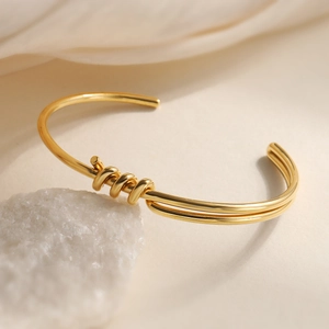 18K gold-plated knotted open bangle featuring a minimalist twisted line design on white stone