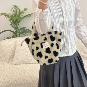 Close-up of fluffy white faux fur tote bag with black heart patterns and textile label
