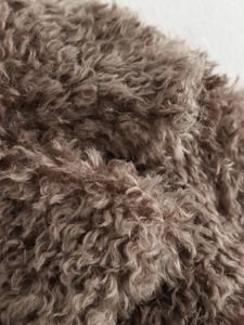 Close-up of tan faux fur texture showing soft curly plush and high-quality warmth detail