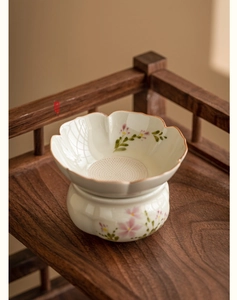 Macro view of ceramic tea strainer with hand-painted daisy pattern and fine mesh holes